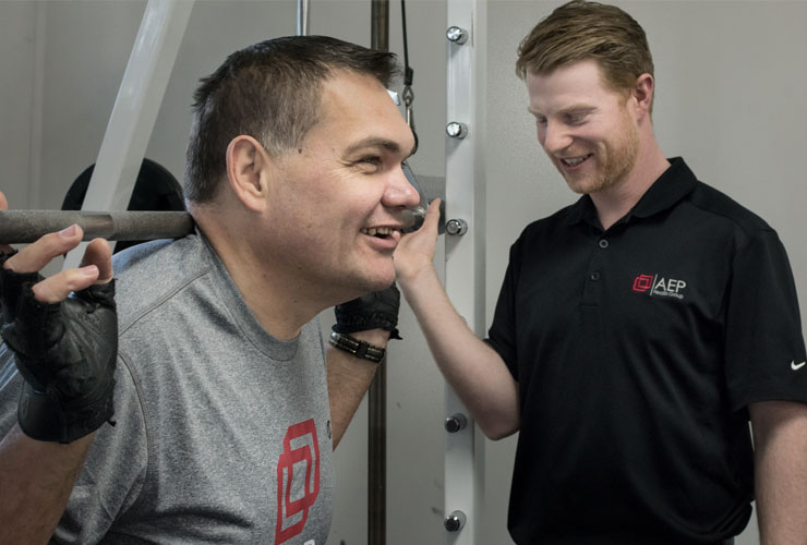 Exercise Physiologist supervises patient doing squats